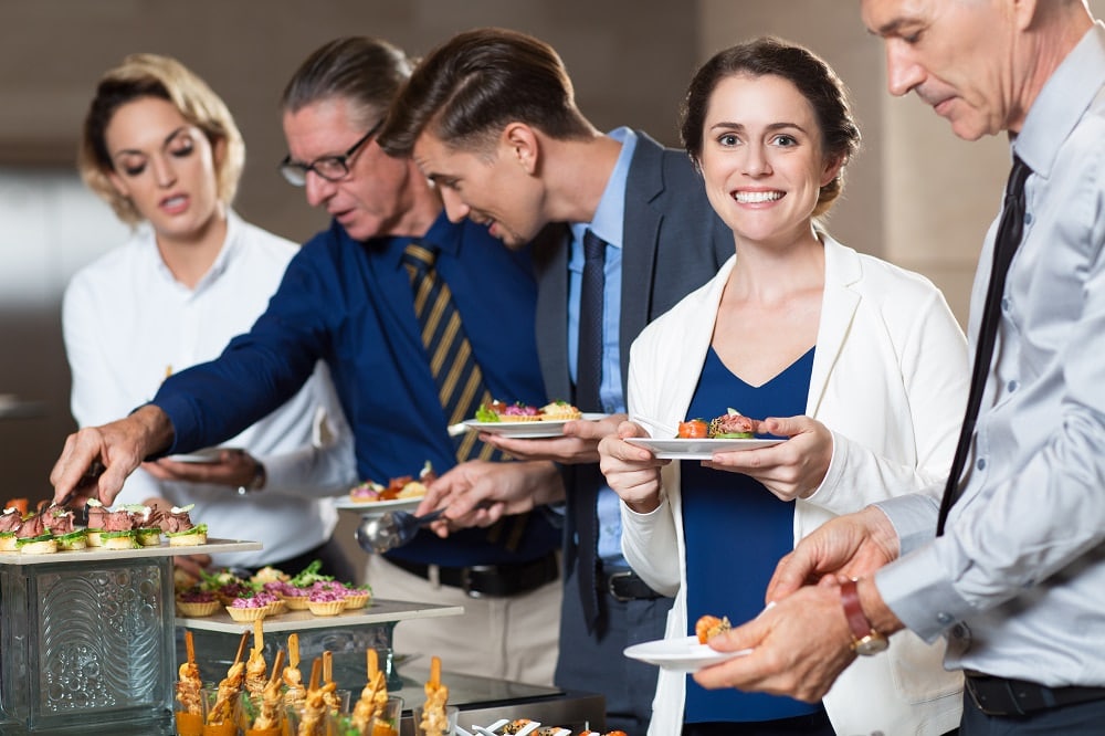 business people taking snacks from buffet table min